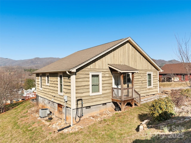 view of front facade with a front lawn, a mountain view, a shingled roof, crawl space, and central AC unit