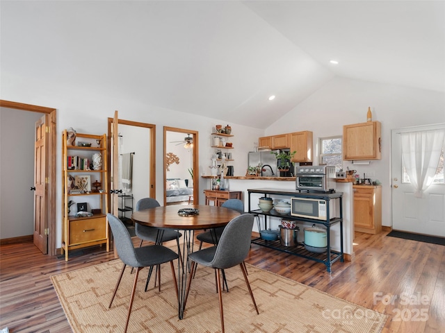 dining space featuring a ceiling fan, light wood-style floors, high vaulted ceiling, and a toaster