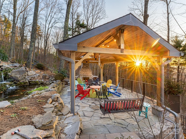 view of patio featuring a gazebo and an outdoor stone fireplace