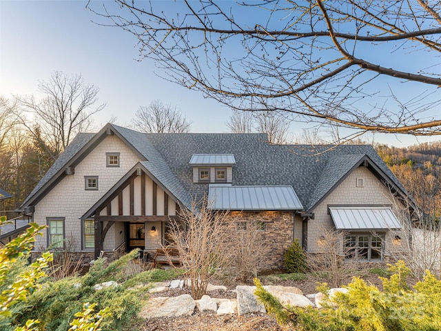 back of house featuring a standing seam roof, metal roof, stone siding, and a shingled roof