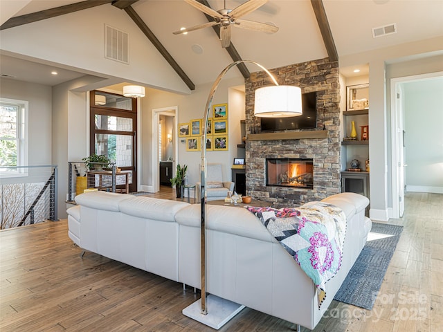 living room with visible vents, a fireplace, high vaulted ceiling, and wood finished floors