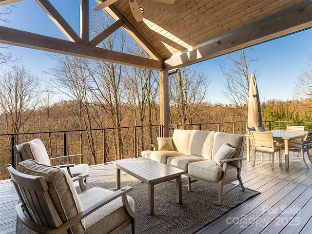 wooden deck with outdoor dining space, an outdoor living space, and a view of trees