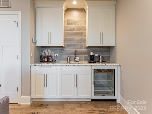 bar with beverage cooler, visible vents, a sink, indoor wet bar, and tasteful backsplash