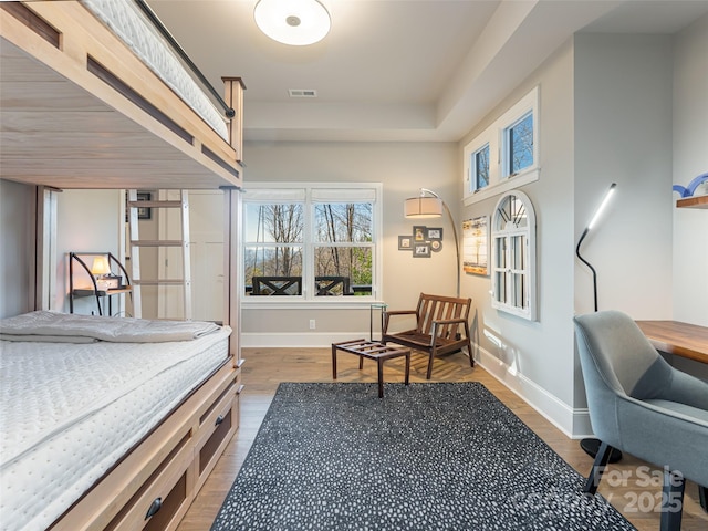 bedroom with visible vents, baseboards, and wood finished floors