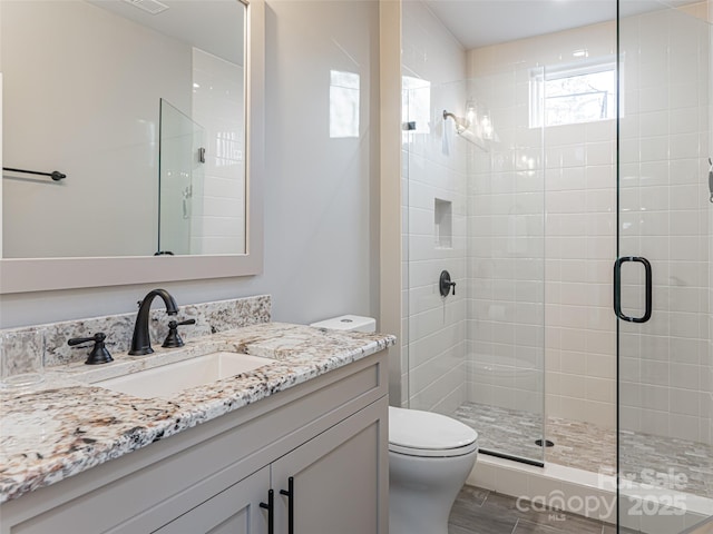 bathroom featuring visible vents, toilet, a stall shower, and vanity