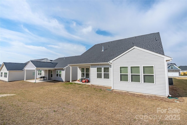 rear view of property featuring a patio area, a yard, and roof with shingles