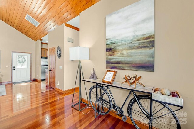 interior space featuring visible vents, lofted ceiling with skylight, wood finished floors, wooden ceiling, and baseboards