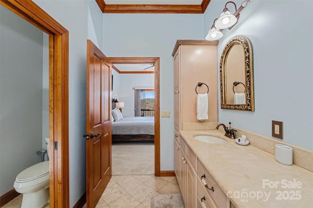 ensuite bathroom featuring vanity, crown molding, and toilet