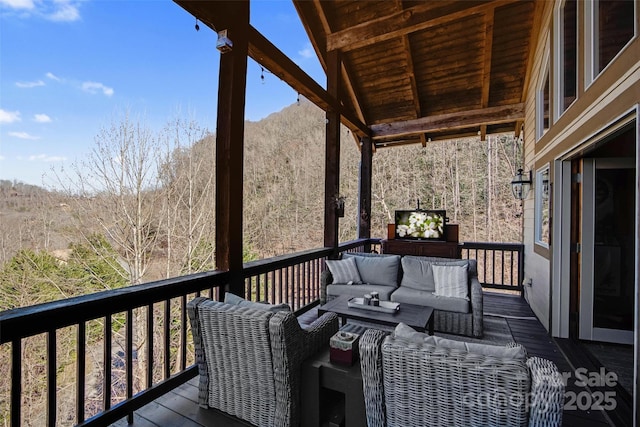 wooden terrace featuring an outdoor living space and a wooded view