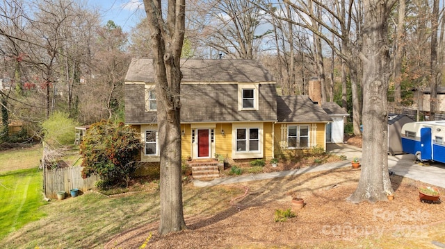 colonial inspired home with a chimney and a front yard