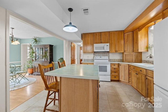 kitchen with white appliances, light countertops, visible vents, and a sink