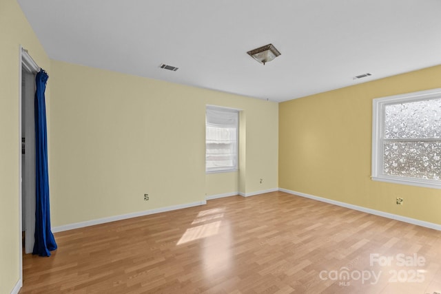 empty room with visible vents, plenty of natural light, and light wood-style floors