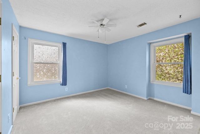 carpeted spare room with baseboards, visible vents, a textured ceiling, and a ceiling fan