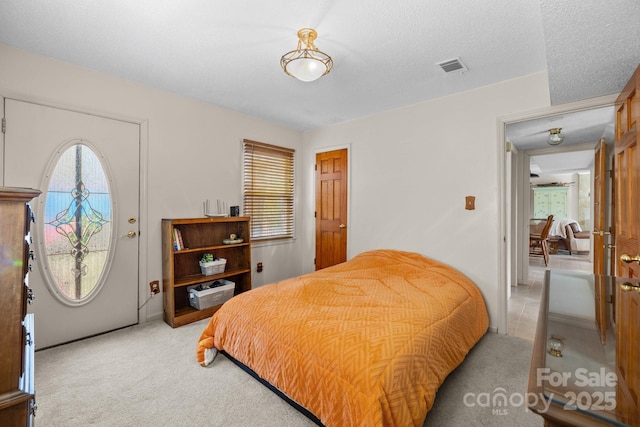 bedroom with a textured ceiling, visible vents, and light carpet