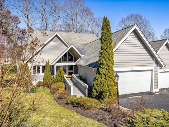 view of front of house with a front lawn, driveway, a shingled roof, and a garage