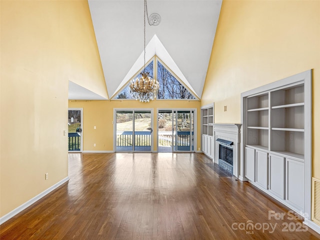 unfurnished living room featuring a chandelier, a fireplace, baseboards, and wood finished floors