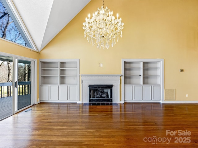 unfurnished living room with visible vents, wood finished floors, and a chandelier