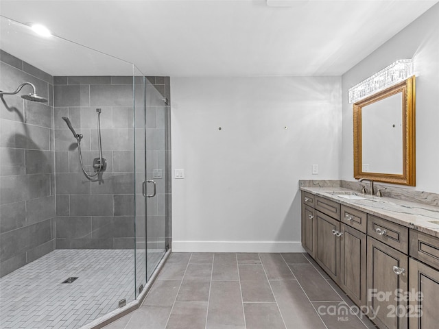 full bath featuring tile patterned floors, baseboards, a stall shower, and vanity