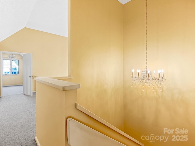 hall featuring a notable chandelier, baseboards, lofted ceiling, and carpet floors