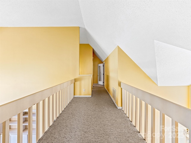 hall featuring visible vents, carpet floors, a textured ceiling, and lofted ceiling