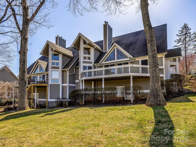 back of property with a shingled roof, a lawn, and a chimney