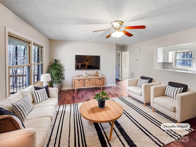 living room featuring a ceiling fan, wood finished floors, visible vents, and a textured ceiling