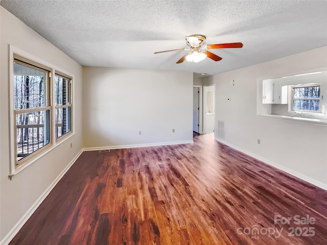 unfurnished room featuring visible vents, ceiling fan, baseboards, wood finished floors, and a textured ceiling