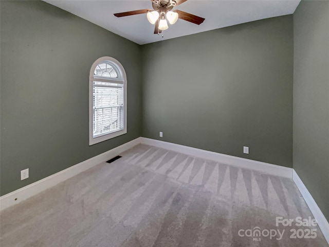 carpeted empty room featuring visible vents, ceiling fan, and baseboards