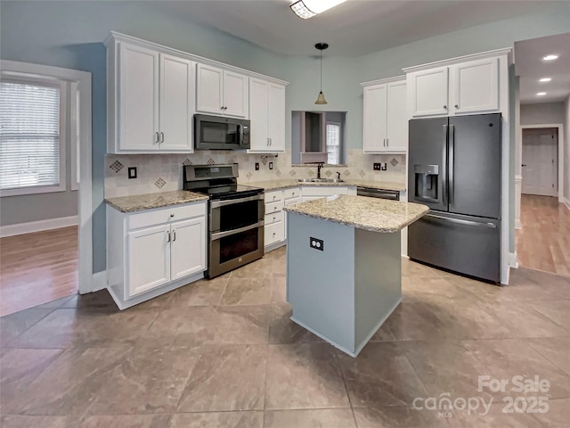 kitchen with black appliances, a sink, a kitchen island, backsplash, and white cabinetry