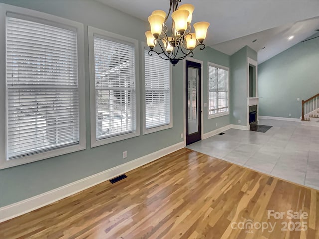 unfurnished dining area with visible vents, baseboards, stairway, vaulted ceiling, and wood finished floors