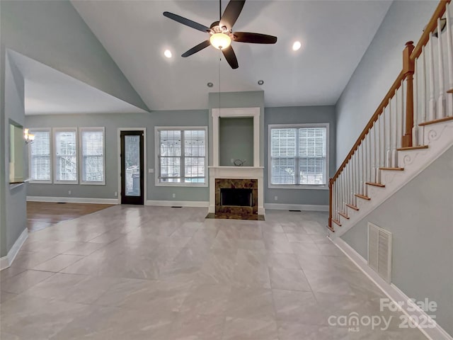 unfurnished living room featuring stairway, a healthy amount of sunlight, visible vents, and a premium fireplace