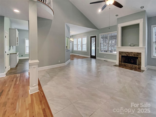 unfurnished living room with a high end fireplace, ceiling fan, baseboards, recessed lighting, and ornate columns