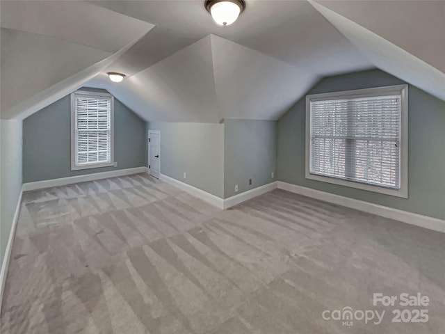 bonus room featuring lofted ceiling, carpet flooring, and baseboards