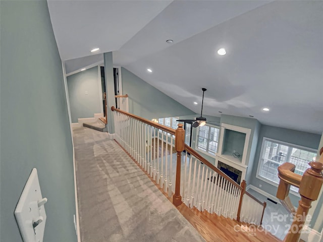 hallway featuring vaulted ceiling, plenty of natural light, an upstairs landing, and wood finished floors