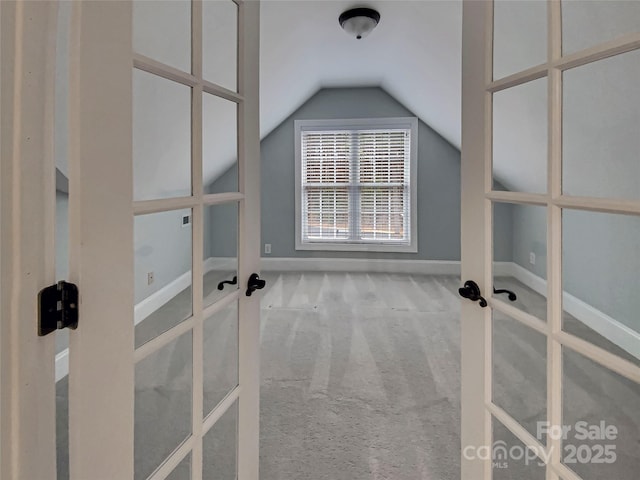 interior space with french doors, baseboards, carpet, and lofted ceiling