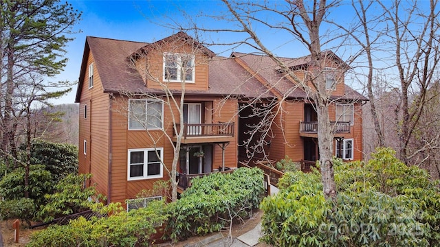 view of front of property with a balcony and roof with shingles