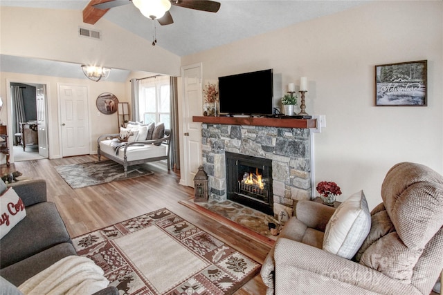 living area with wood finished floors, visible vents, lofted ceiling with beams, a fireplace, and ceiling fan