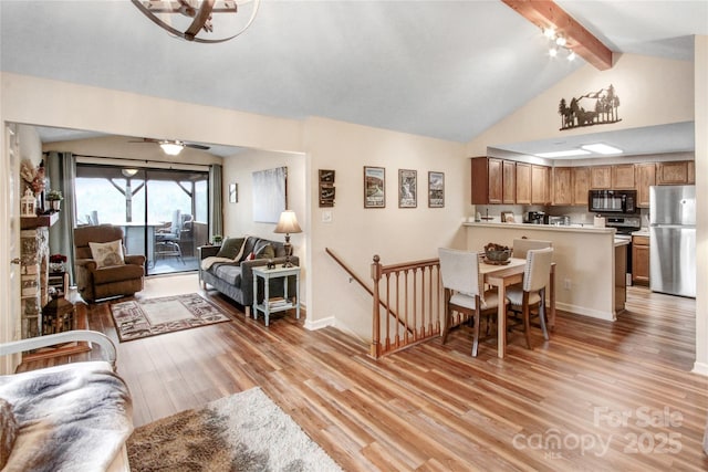 living room featuring lofted ceiling with beams, a ceiling fan, baseboards, and light wood finished floors