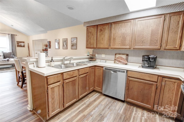 kitchen with a sink, light wood-style flooring, a peninsula, and stainless steel dishwasher