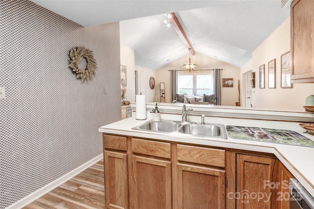 kitchen with light wood-type flooring, vaulted ceiling with beams, light countertops, and a sink