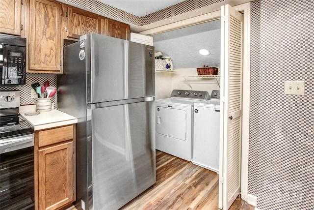 kitchen with light wood finished floors, stainless steel appliances, light countertops, washing machine and dryer, and tasteful backsplash