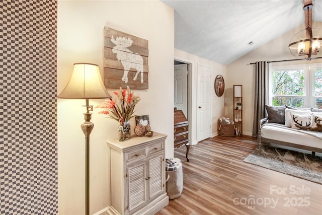 living area with visible vents, baseboards, lofted ceiling, and wood finished floors