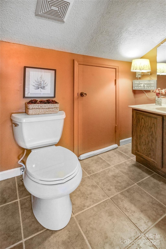 bathroom with tile patterned floors, visible vents, toilet, and a textured ceiling