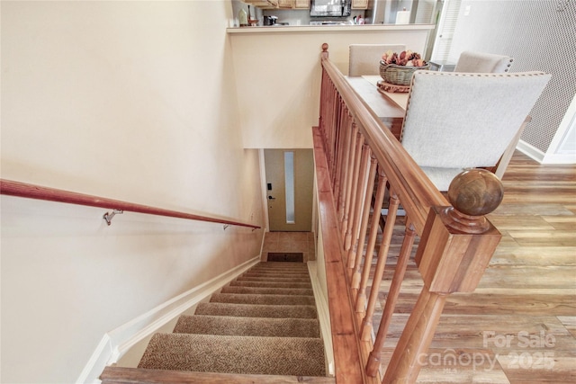 staircase featuring baseboards and wood finished floors