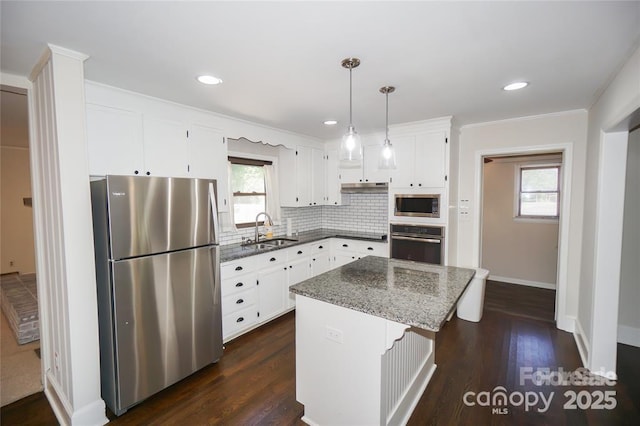 kitchen featuring a kitchen island, a sink, decorative backsplash, stainless steel appliances, and white cabinets