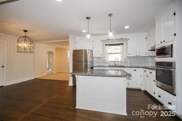 kitchen with tasteful backsplash, a kitchen island, appliances with stainless steel finishes, white cabinetry, and a sink