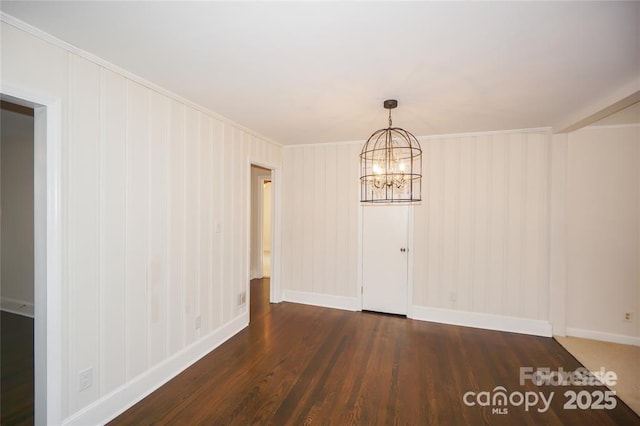 empty room with a chandelier, baseboards, and wood finished floors