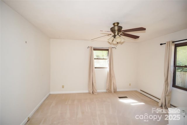 spare room with a ceiling fan, light colored carpet, baseboards, and a wealth of natural light