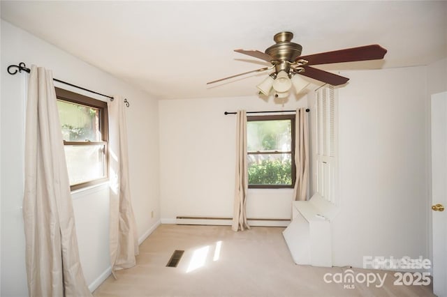 empty room featuring a baseboard heating unit, a healthy amount of sunlight, visible vents, and ceiling fan