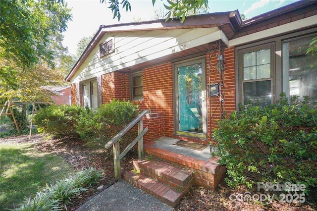 view of exterior entry featuring brick siding